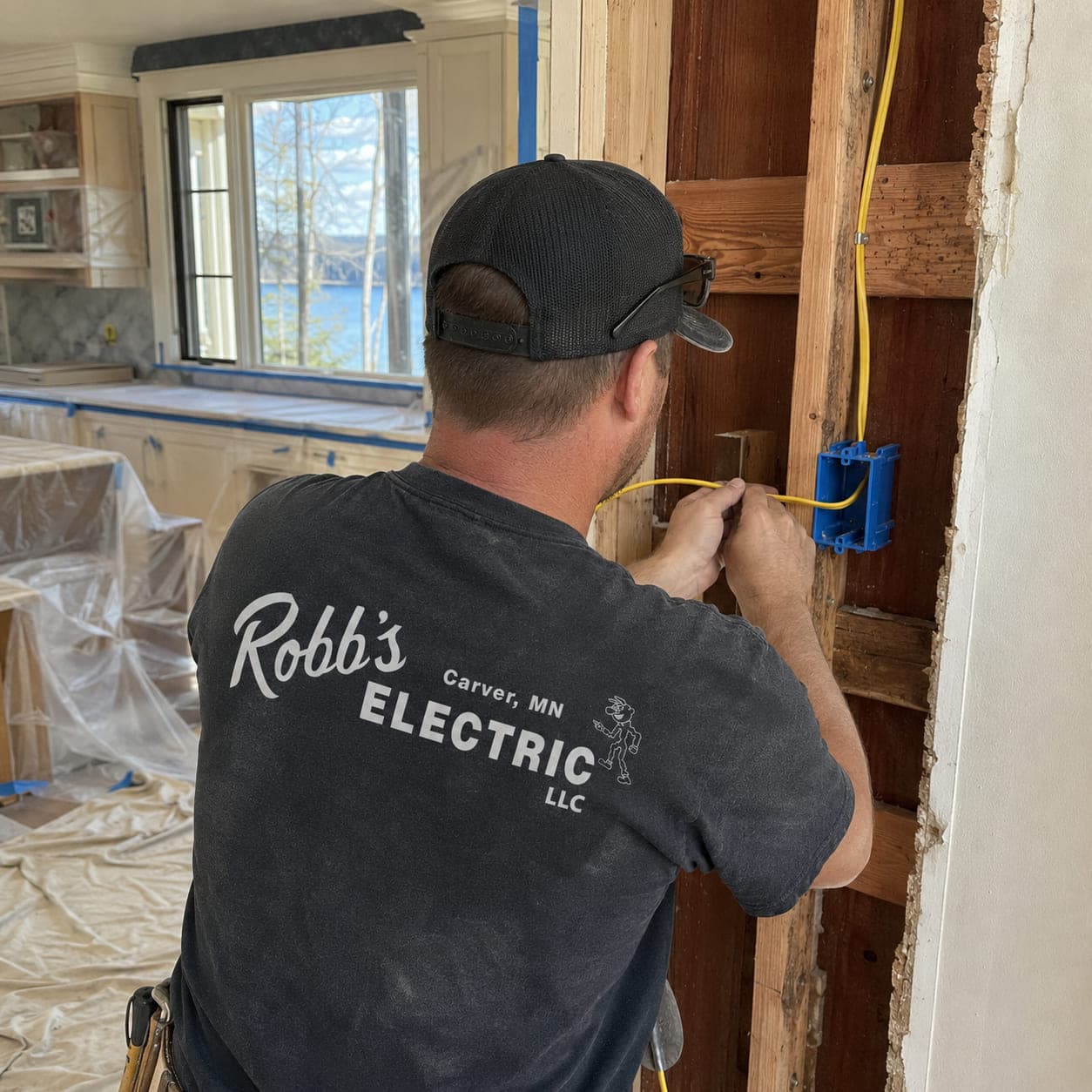 Robb's Electric technician wiring a new device box in an opened kitchen wall during a lakeside remodel
